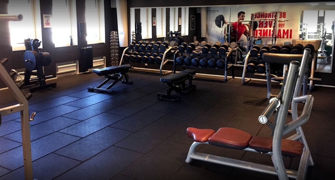 A gym with weightlifting equipment, benches, and dumbbells.