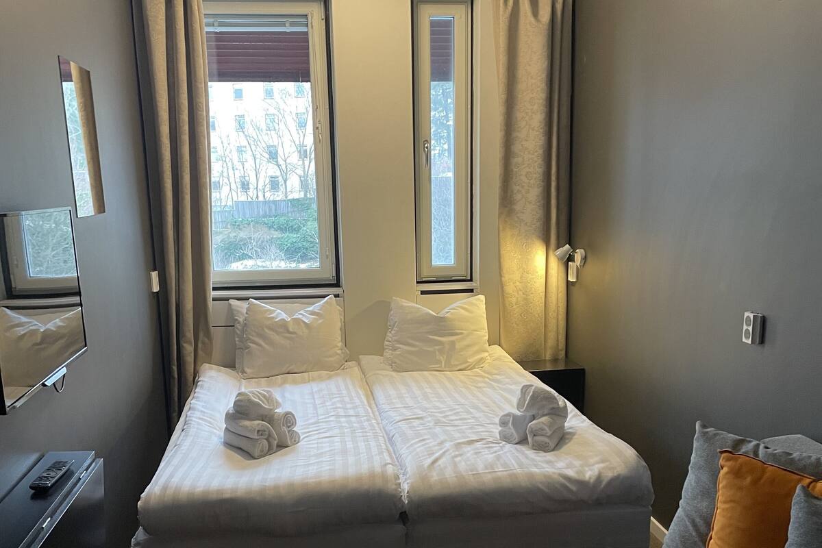 A hotel room with two beds, a sofa, a desk, and a TV.