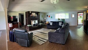 A living room with a fireplace, a sofa set, a TV, and a dining area. - Tenkiller Bluff House (Park Hill)