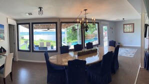 A dining area with a large oval table, dark blue chairs, and a view of the outdoors. - Tenkiller Bluff House (Park Hill)