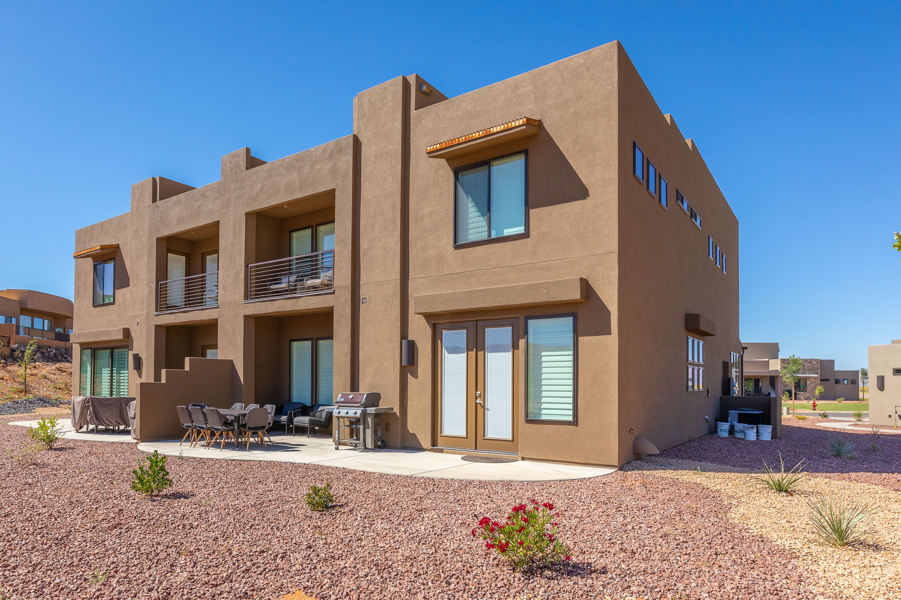A modern multi-story building with a patio area featuring outdoor furniture and a grill.