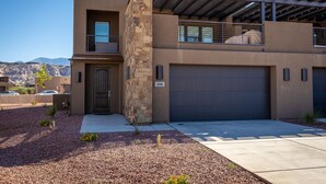 A modern two-story house with a stone accent wall, a garage, and a clear view of mountains in the background. - Stunning 4BR Sleeps 18 - Bold Designer Interiors (St. George)
