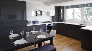 Une cuisine moderne avec des meubles de couleur sombre, un îlot central doté de sièges, un four encastré et une fenêtre offrant une vue agréable.