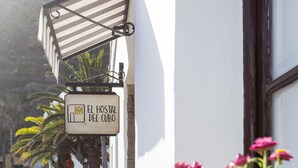 A sign for 'El Hostal del Cubo' with a tiled walkway and potted flowers in the foreground. - El Hostal Del Cubo (San Juan de la Rambla)