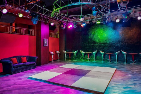 A stage with a checkered floor, a sofa, and bar stools.