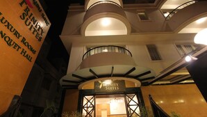 A hotel entrance with a sign for Trinity Suites, featuring a modern design with multiple balconies and a well-lit facade. - Hotel Trinity Suites (Bengaluru)