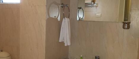Un baño con lavamanos, espejo, toallero y retrete.