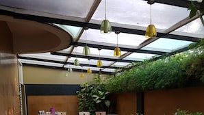 An outdoor patio area with tables and chairs, a red tablecloth, and potted plants. - Hotel Trinity Suites (Bengaluru)