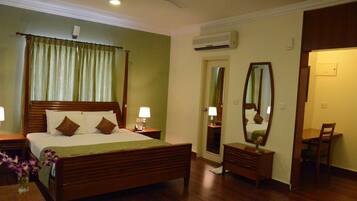 A hotel room with a wooden bed, bedside lamps, a mirror, a desk, and a chair.