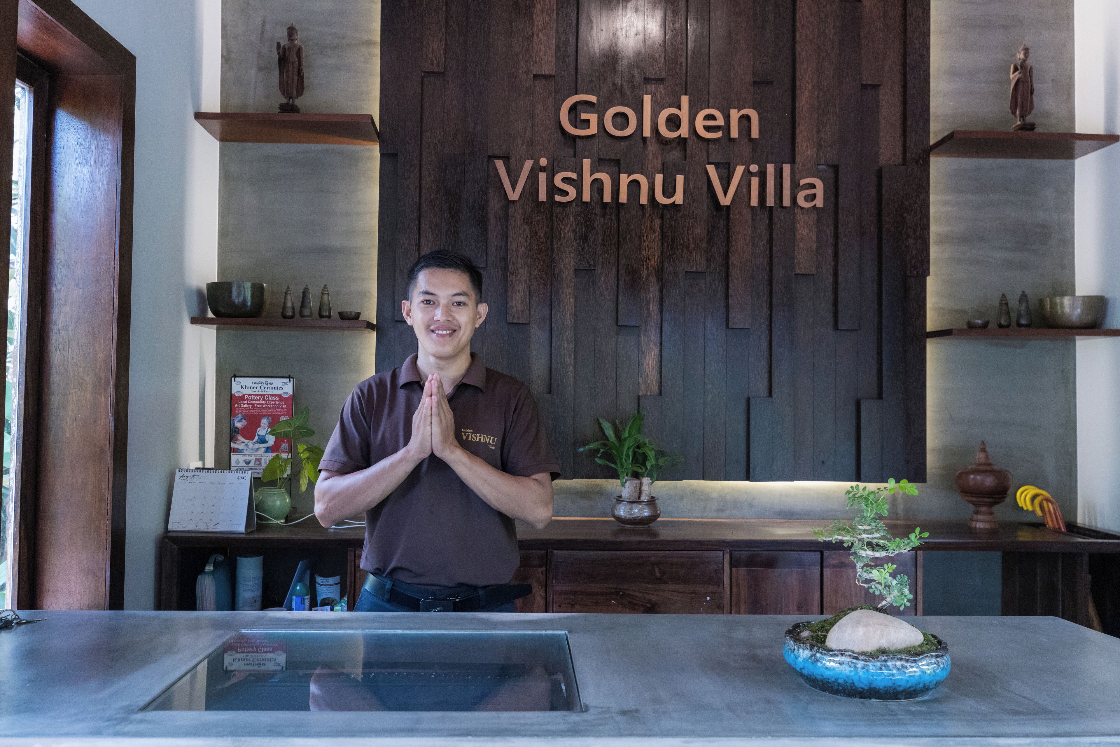 Zona de recepción con una pared de madera que muestra el nombre "Golden Vishnu Villa".
