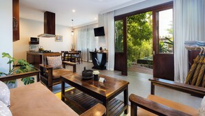 A spacious living area with a wooden coffee table, sofas, and a TV mounted on the wall. - Golden Vishnu Villa (Siem Reap)