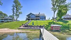 Ein großes, zweistöckiges Haus mit Schwimmbad, Terrasse und einer grasbewachsenen Anhöhe.
