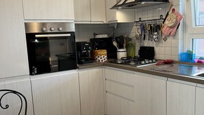Una cocina con armarios de tonos claros, una cafetera Bosch y un reloj rojo en la pared.
