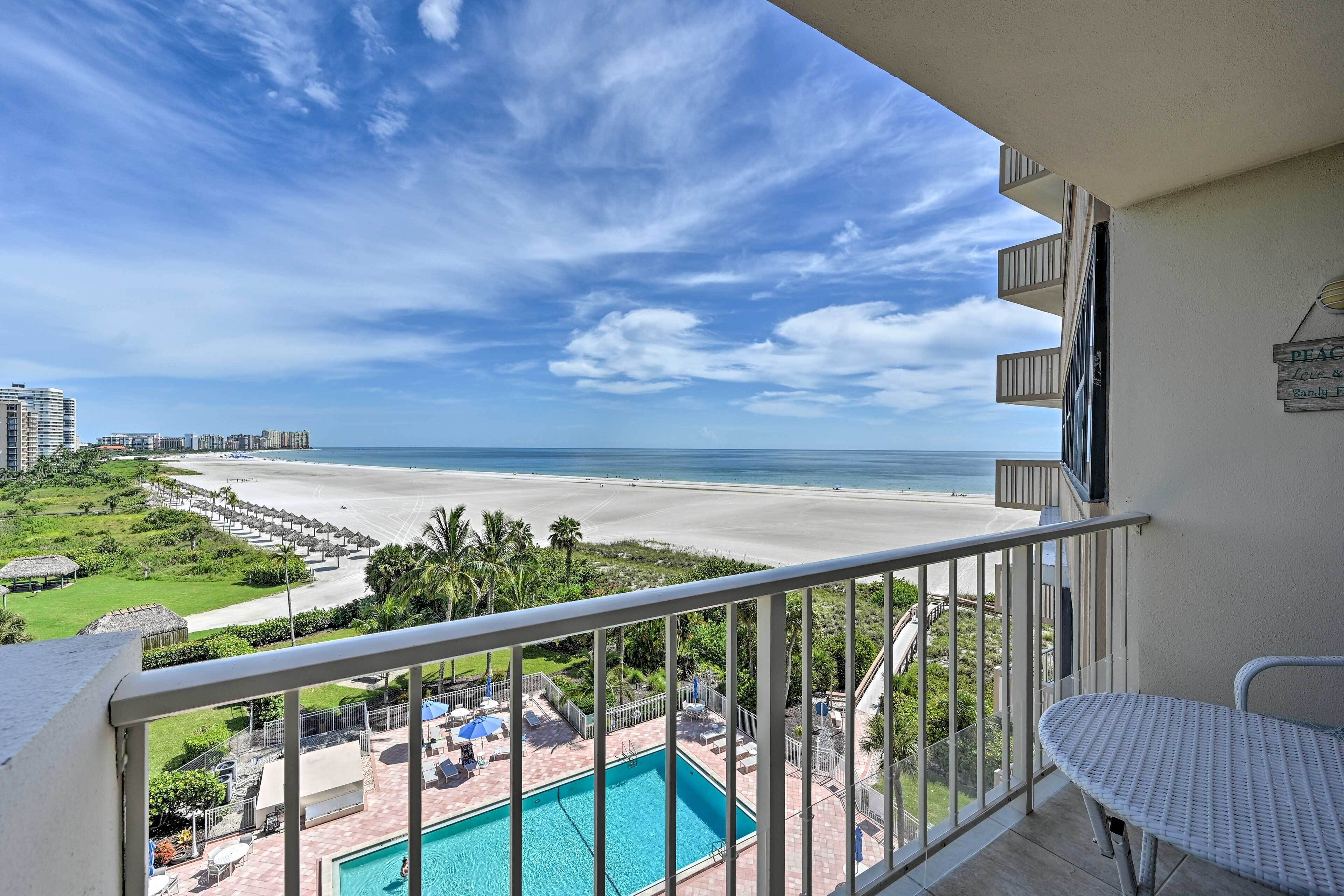 Ein Balkon mit Blick auf einen Strand, ein Schwimmbad und ein Hotelgebäude im Hintergrund.