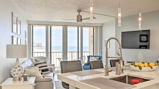 A modern kitchen with a large island, a dining area with a view, and a balcony with a view.