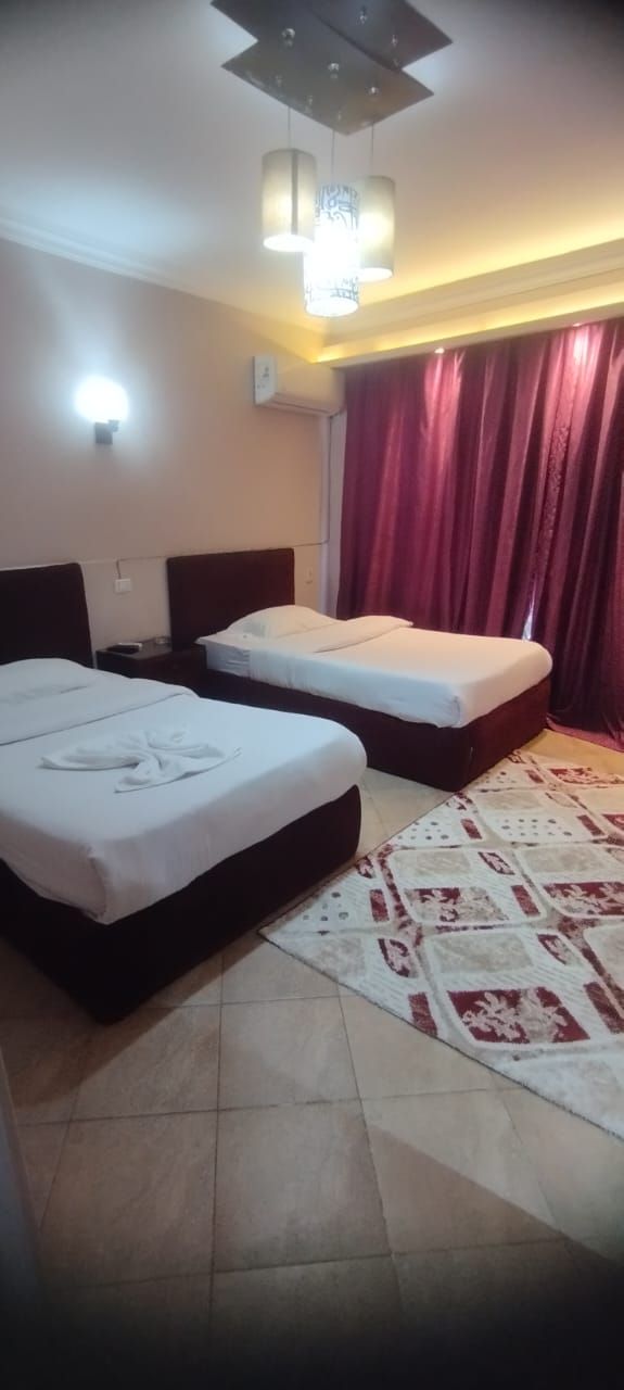 Une chambre d’hôtel avec deux lits, un tapis à motifs et un luminaire au plafond.