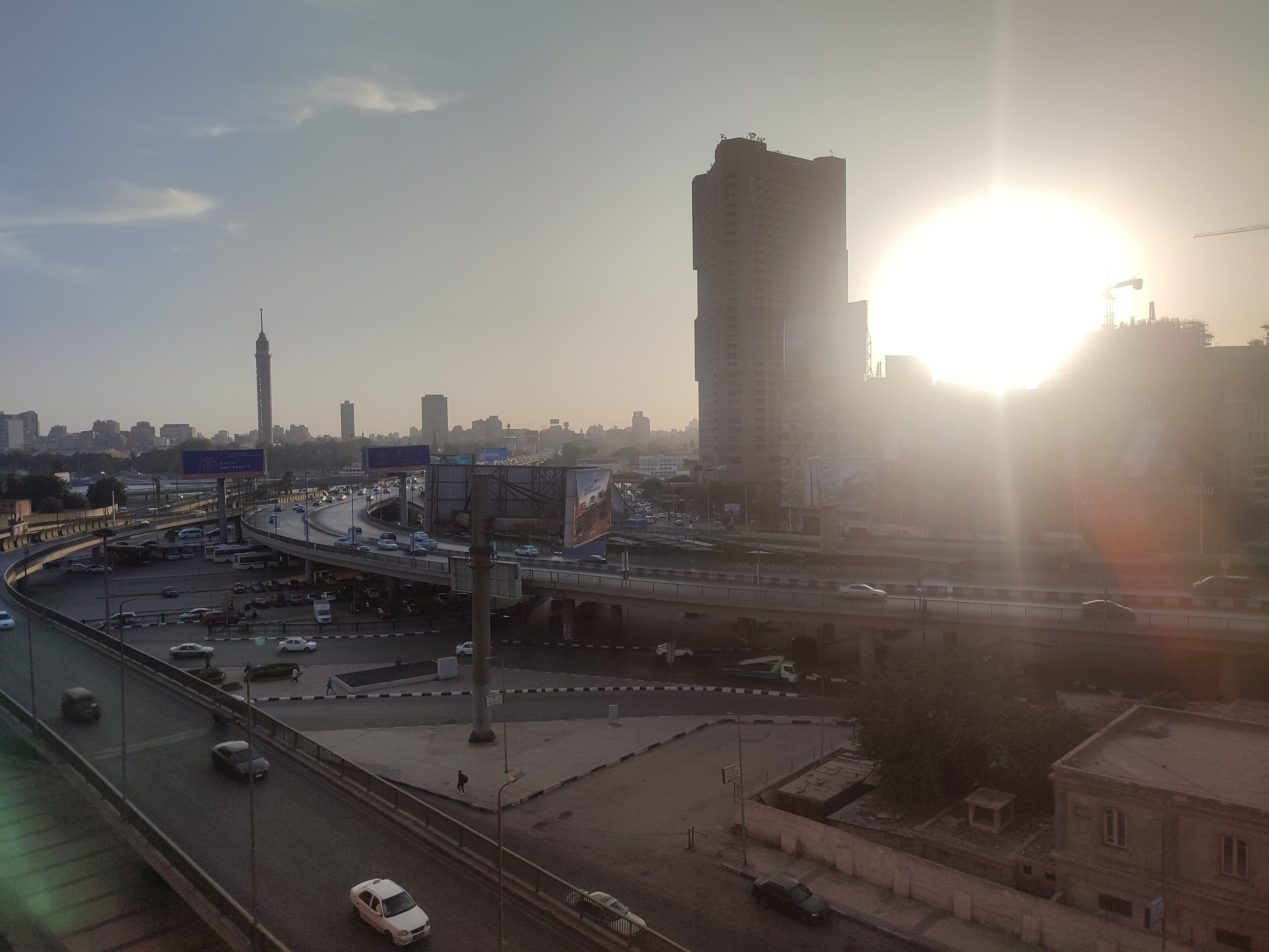 A cityscape with a prominent tower, a highway, and a clear sky.