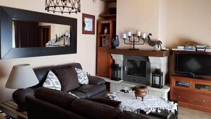 A living room with a sofa, a fireplace, a television, and a large mirror.