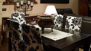 A dining area with a table, chairs, a chandelier, a mirror, and a framed picture on the wall.