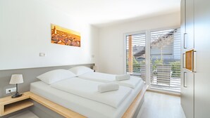 Un dormitorio moderno con cama, mesita de noche, lámpara y una pintura de un paisaje urbano.