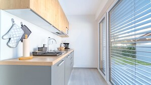 Una cocina moderna con armarios de madera, horno empotrado y un amplio ventanal con persianas.