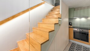 Une cuisine moderne avec un escalier en bois menant à une porte en verre.