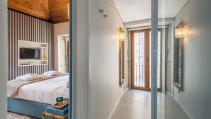 Une chambre à coucher avec un lit, un téléviseur et une porte vitrée donnant sur un couloir.