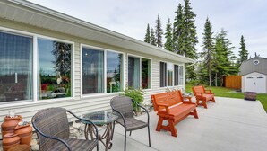 A patio with wicker chairs and a wooden bench, a glass table, and terracotta planters. - Soldotna Home w/ Yard, Walk to Kenai River! (Soldotna)