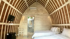 A cozy, rustic room with a vaulted ceiling, a bed, a desk, and a television.