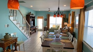 A spacious dining area with a high ceiling, a staircase, and a view of the outside through large windows. - Fantastic Oceanfront Home/Lgprivpool/Wifi/A+Location-Call/text 4046643546 (Gulf Shores)