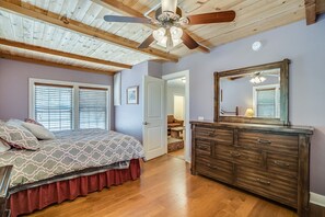 Cozy retreat with a large bed, dresser, and sloped ceiling with exposed beams.