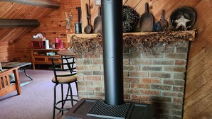 A cozy room with a brick fireplace, wooden ceiling beams, and a rustic decor. - Quiet country setting awaits you! (Munnsville)