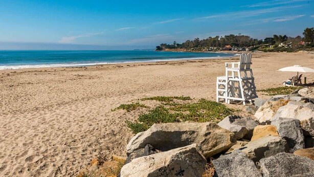 A beach with a lifeguard tower, a chair, and an umbrella. - Padaro Beach Contemporary (Carpinteria)