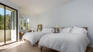 A bedroom with two beds, a large window, and a view of greenery. - Padaro Beach Contemporary (Carpinteria)