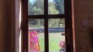 Uma janela em arco de madeira com vista para um jardim e um banco com flores.