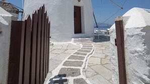 A white windmill with a stone pathway leading to a wooden door. - Iconic Windmill in Mykonos (Mykonos)