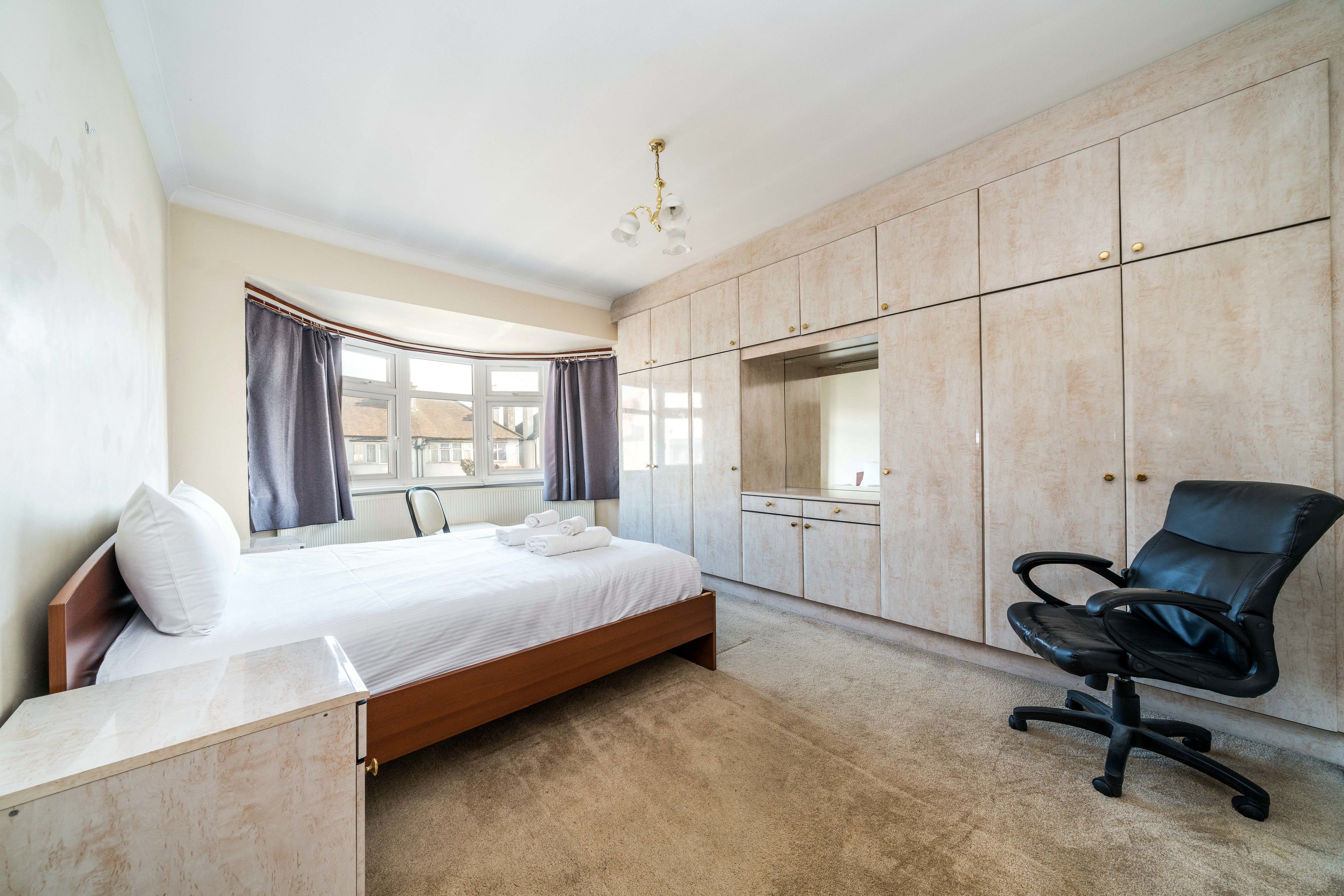 A bedroom with a bed, a desk, a chair, and a wardrobe.