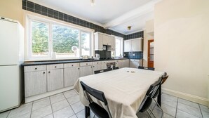 A kitchen with a dining table, cabinets, and a view of the outdoors.