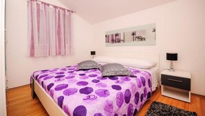 A bedroom with a bed, a nightstand, a lamp, a window with curtains, and a wall art piece. - House Boze (Vinisce)