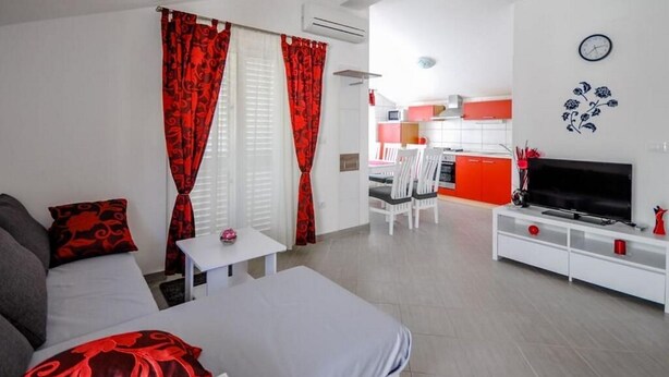 A modern living room with a sofa, a TV, and a dining area with chairs and a table. - House Boze (Vinisce)