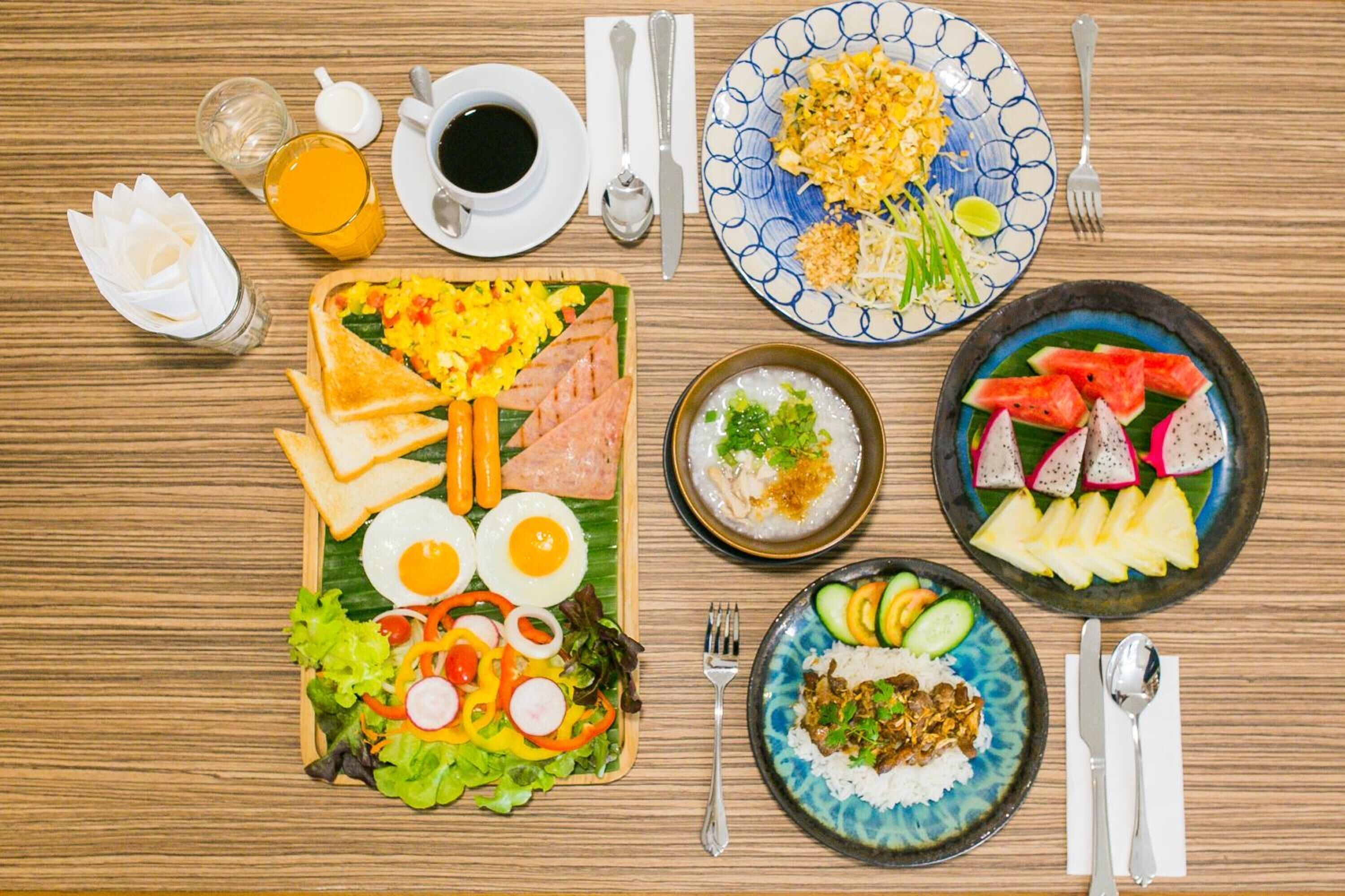 A wooden table with a variety of dishes including toast, eggs, salad, and fruit.