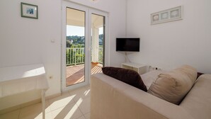 Ein modernes Wohnzimmer mit einer Couch, einem Flachbildfernseher und einem Balkon mit Blick.