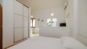 Ein Schlafzimmer mit einem Bett, einer Schiebetür, einem Schreibtisch mit Stuhl und einem Fenster.