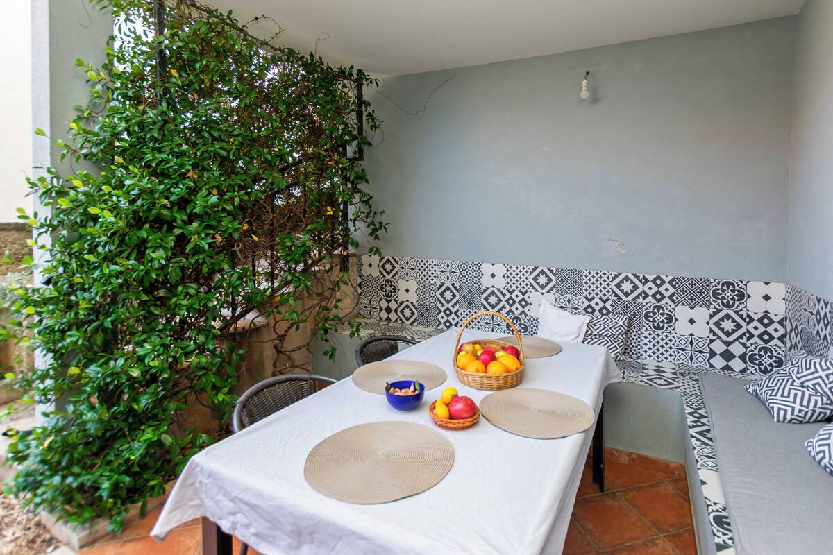 A dining area with a table set for two, surrounded by patterned cushions.