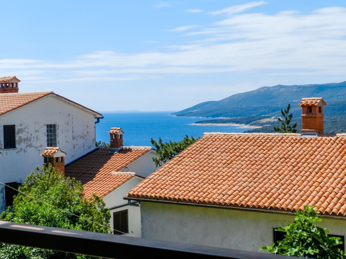 A coastal village with terracotta-tiled roofs and a view of the sea.