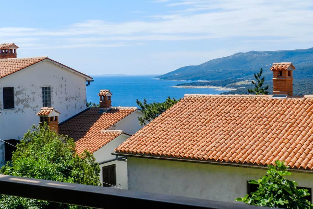 A coastal village with terracotta-tiled roofs and a view of the sea.