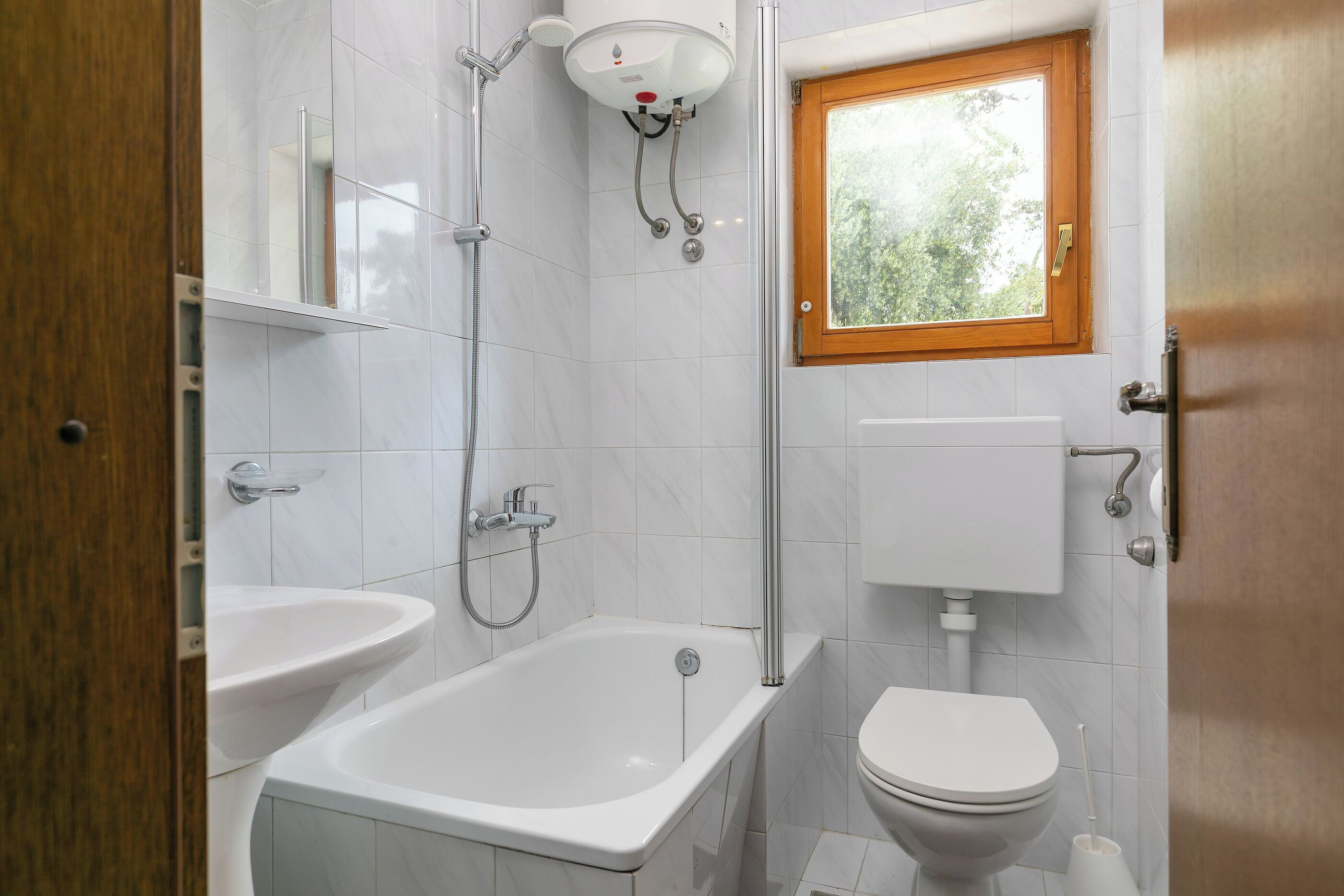 A bathroom with a bathtub, a toilet, a shower, and a window.