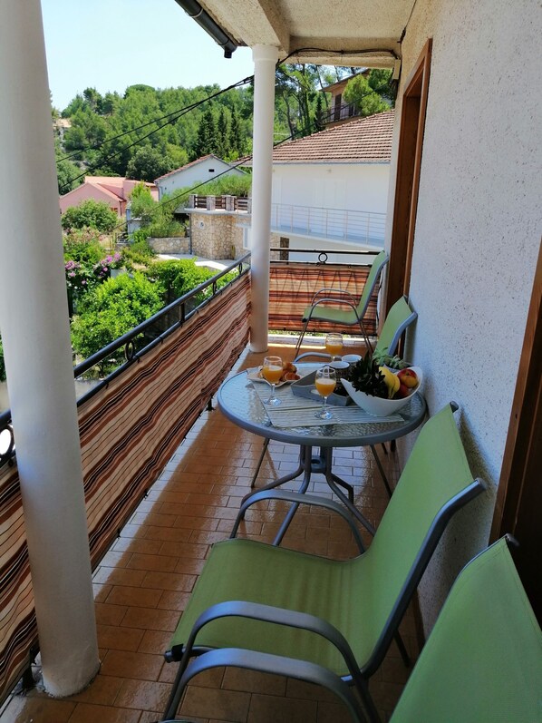 A small balcony with a table set for two, two chairs, and a bowl of fruit. - Apartments Amazing View (Jelsa)
