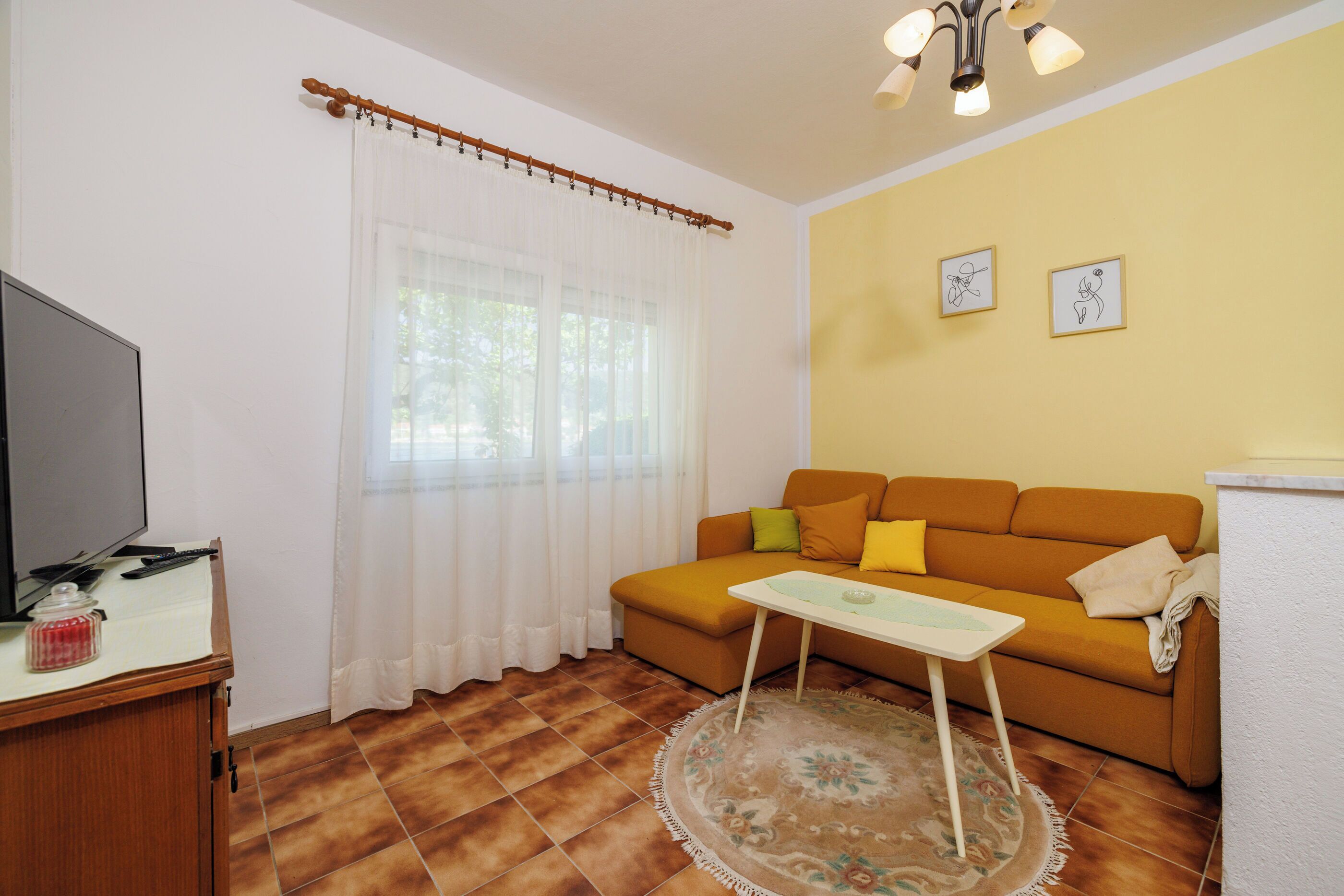 Un salon avec un canapé, une table basse, un téléviseur et un rideau.
