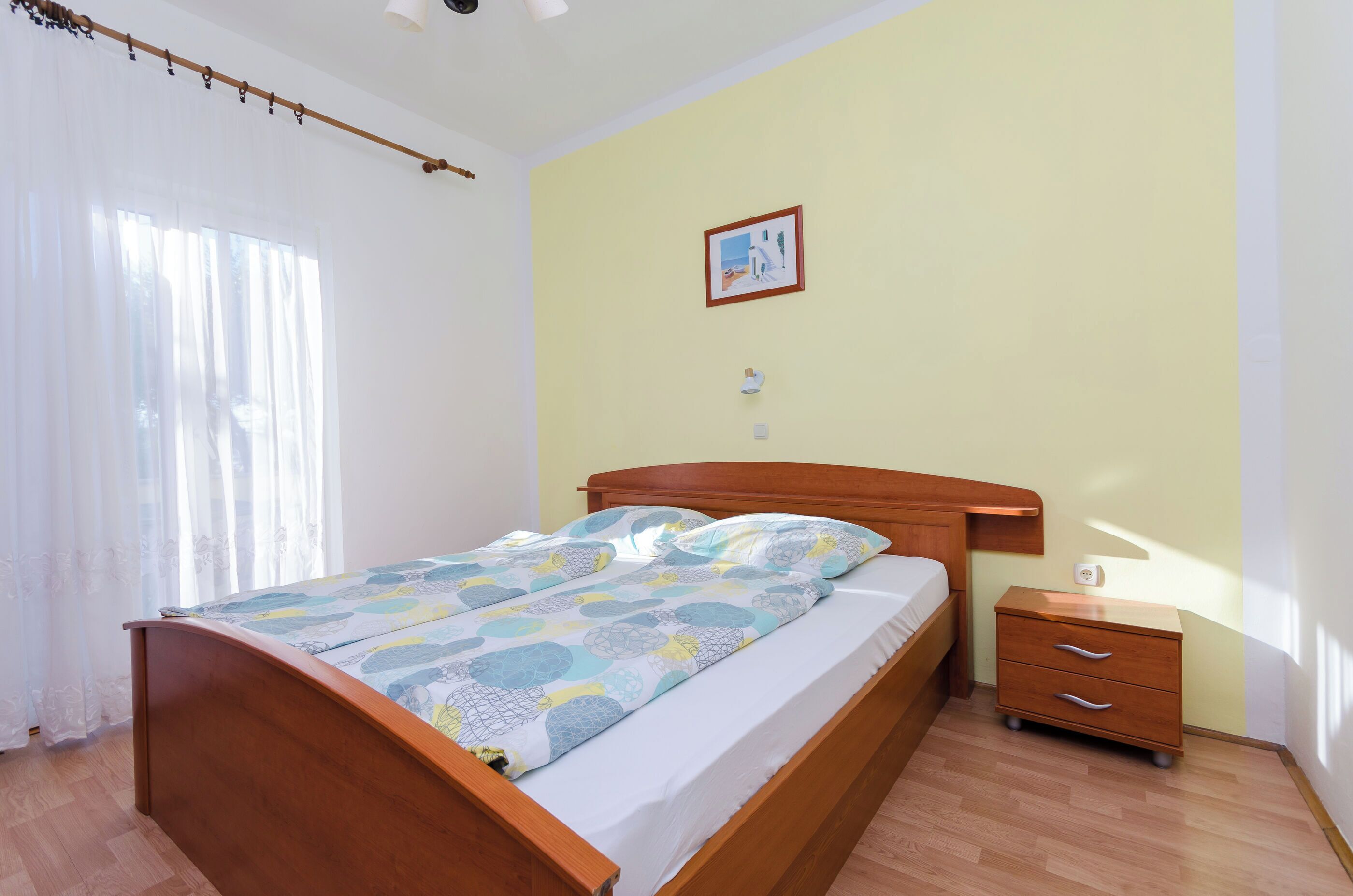 A bedroom with a wooden bed, a bedside table, and a small cabinet.
